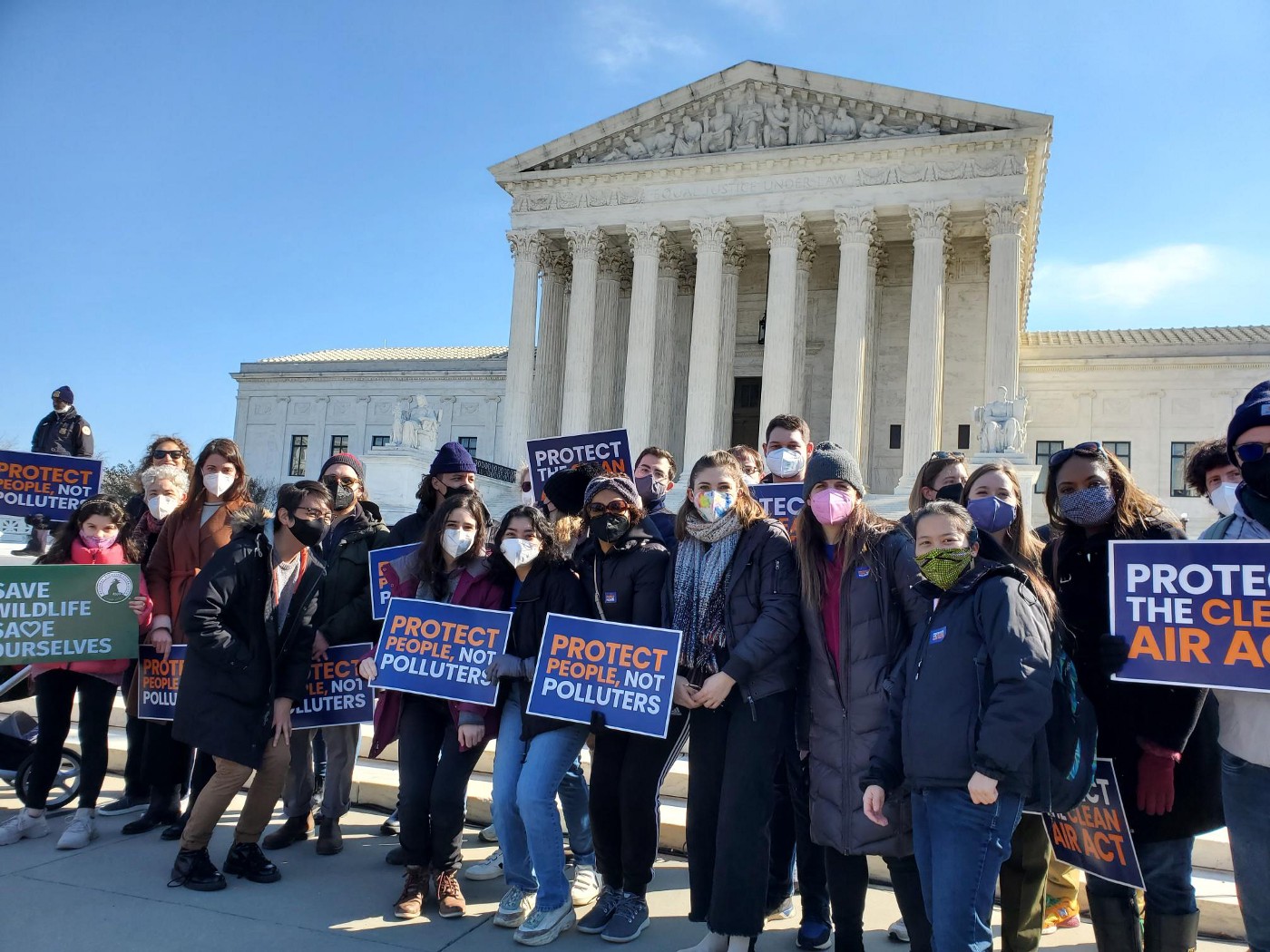 An image of a group of protesters standing in front of the Supreme Court holding signs that say, “Protect People, Not Polluters.”