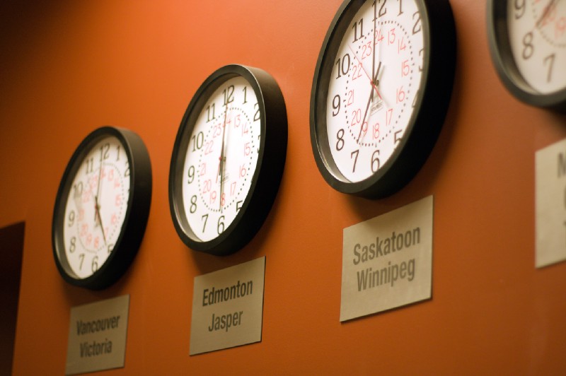 Three clocks on a wall displaying different time zones.