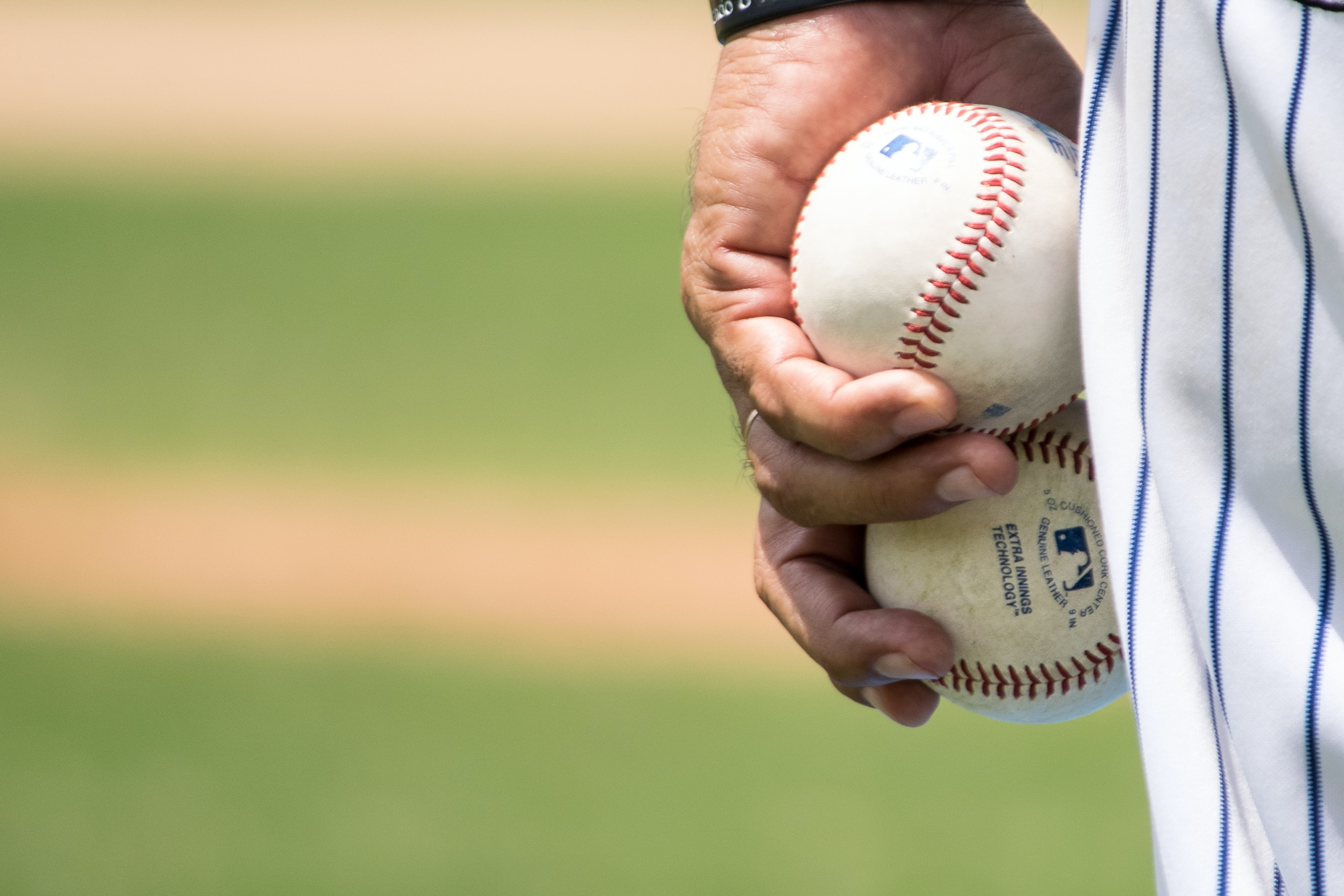 A picture of a baseball player holding two baseballs.
