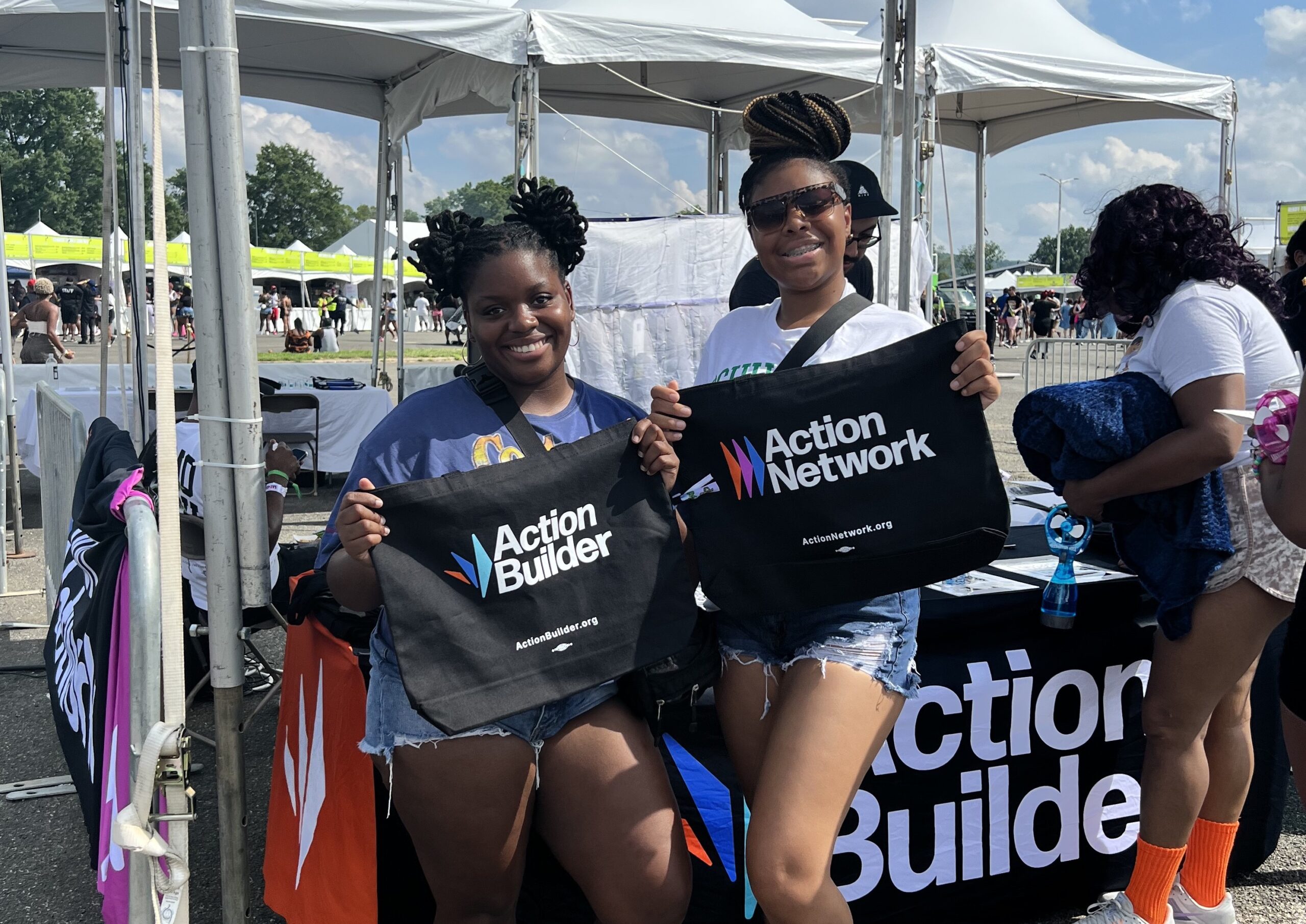 Broccoli City Festival attendees showing off their Action Network & Action Builder tote bags at the Action Network booth.